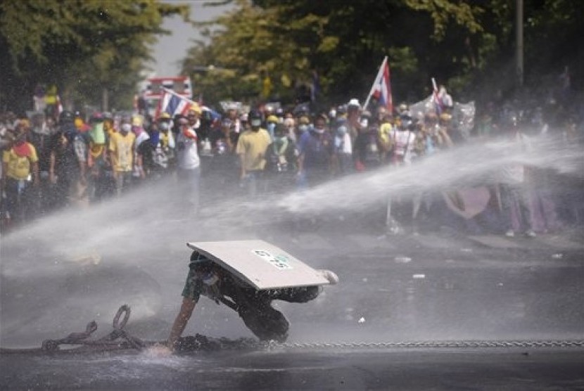 An Anti-government protester falls as he is hit by water cannon by police in Bangkok, Thailand, Monday, Dec 2, 2013. 