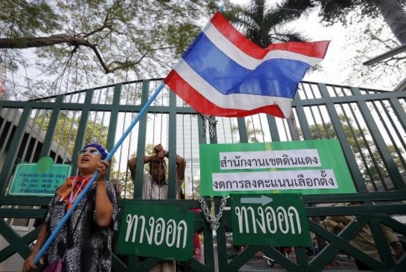 An anti-government protester waves a flag in front of the locked gates of a polling station her group had forced to close in Bangkok January 26, 2014. 