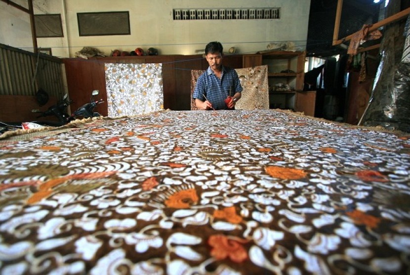 An artisan gives a finishing color of a piece of batik pattern in Paoman, Indramayu, West Java. (illustration)
