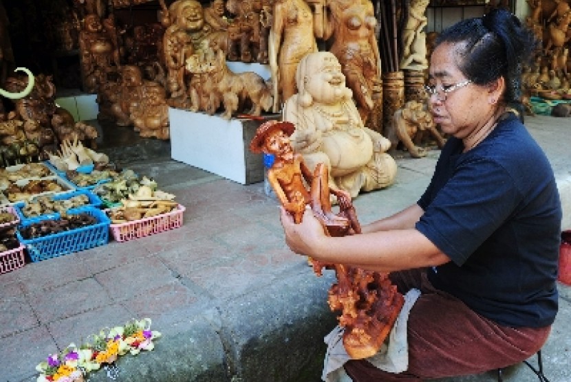 An artisan polish balinese wooden sculpture in a workshop in Bali. (illustration)