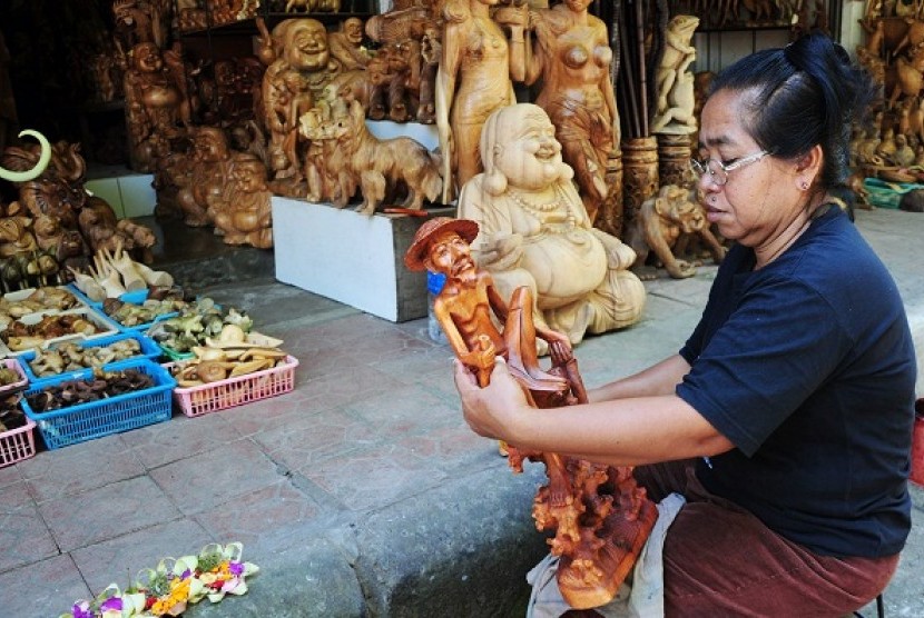 An artisan smoothens the wooden statue using a piece of sandpaper in Ubud, Bali. (iilustration)