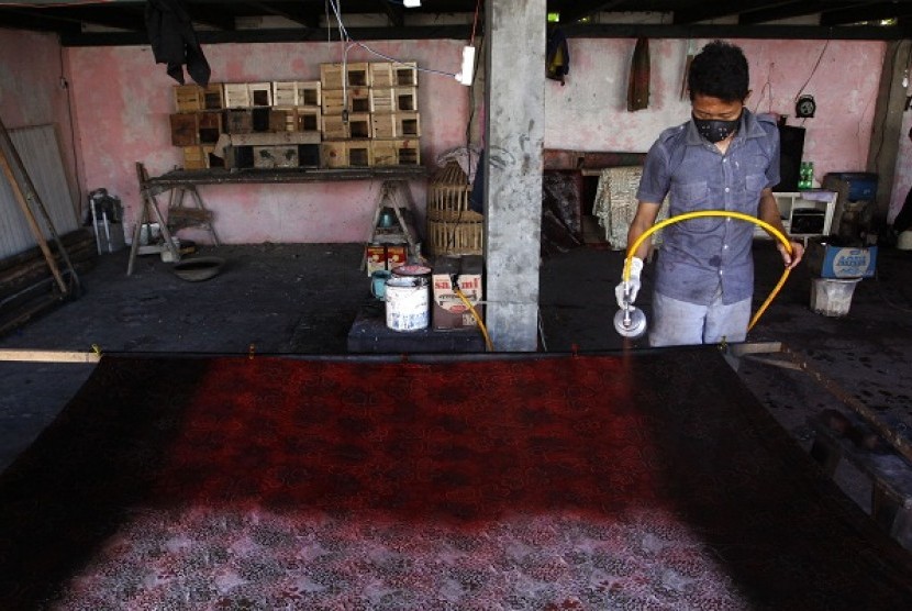 An artisan sprays some colors to a piece if batik print in Pekalongan, Central Java. (illustration)