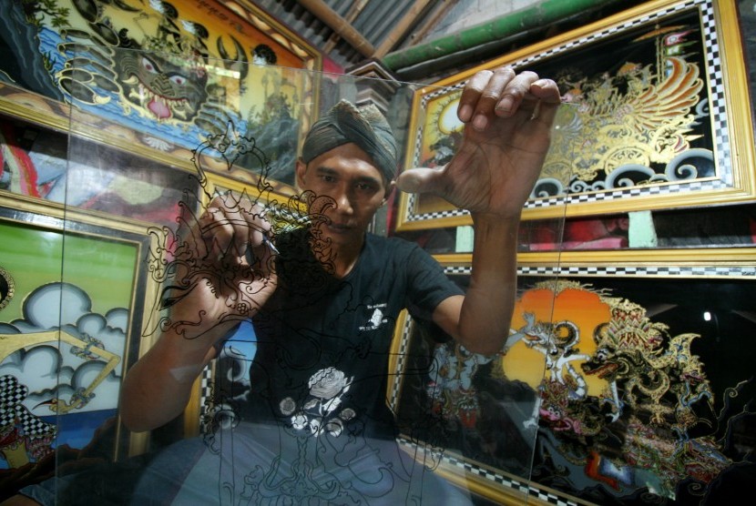 An artist from Kediri, East Java drew a sketch of a puppet in the making of glass painting with reverse painting technique.