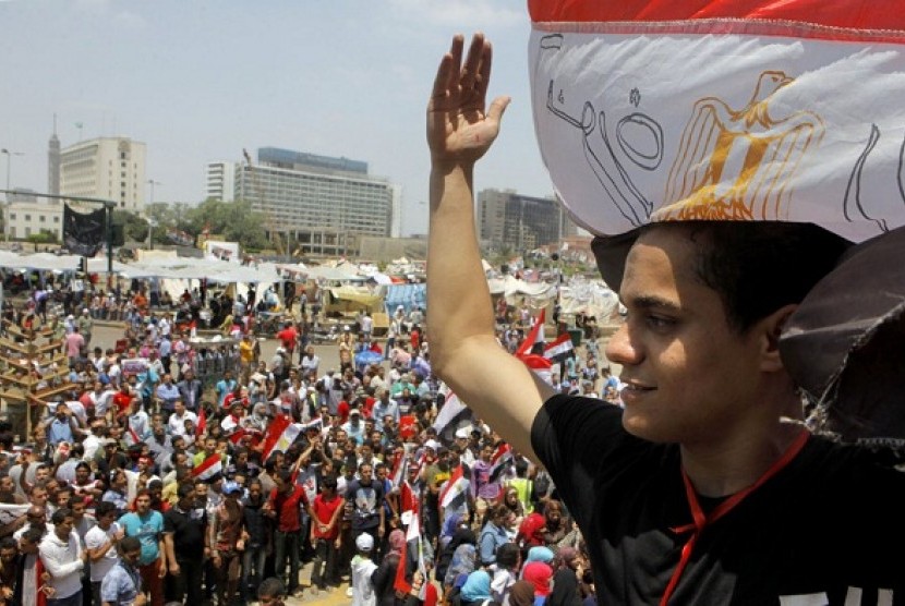 An Egyptian protester covers his head by a national flag during a demonstration against President Mohammad Mursi in Tahrir Square in Cairo, Monday, July 1, 2013.