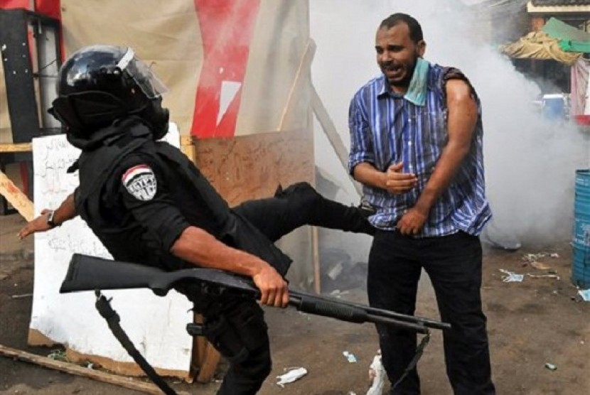 An Egyptian security force kicks a supporter of ousted President Mohammed Mursi as they clear a sit-in camp set up near Cairo University in Cairo's Giza district, Wednesday, Aug. 14, 2013. 