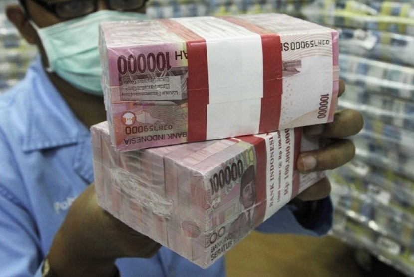 An employee of a bank holds bundles of Indonesian rupiah banknotes at Bank Mandiri in Jakarta. (illustration)