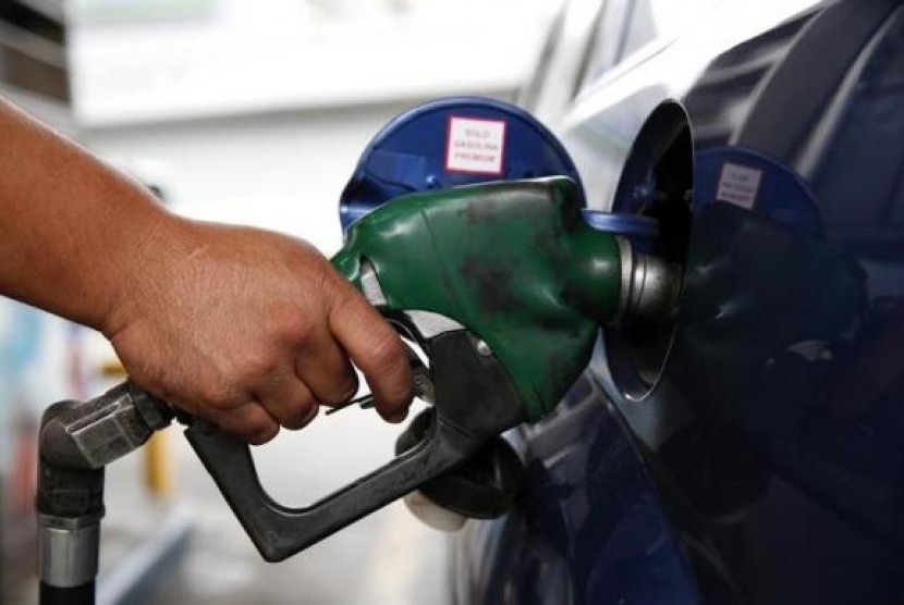 An employee pumps gas into a car at a gas station of the state oil company PDVSA in Caracas December 16, 2013. 