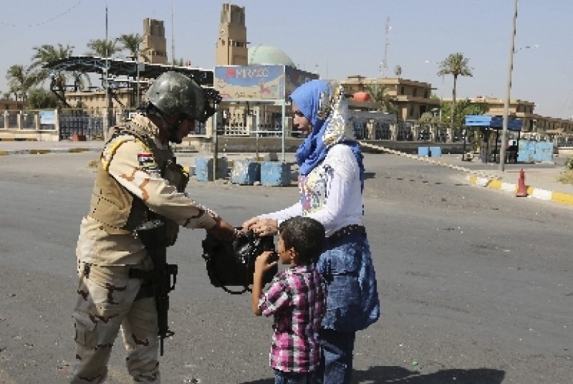 An Iraqi Army soldier searches a woman's bag amid tight security during Eid al-Adha celebrations in Baghdad, Iraq, Monday, Oct. 6, 2014. Eid al-Adha, or Feast of Sacrifice, commemorates what Muslims believe was Prophet Abraham's willingness to sacrifice hi