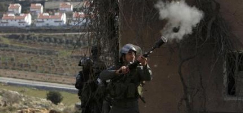 An Israeli border police officer fires a tear gas canister towards stone-throwing Palestinian demonstrators during clashes at a weekly protest against the nearby Jewish settlement of Halamish, West Bank.