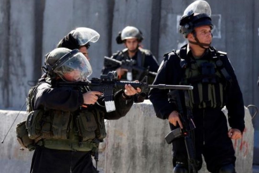  An Israeli border policeman aims his weapon towards Palestinian stone throwers during clashes following a protest against what organizers say are recent visits by Jewish activists to al-Aqsa mosque, at Qalandia checkpoint near the West Bank city of Ramall