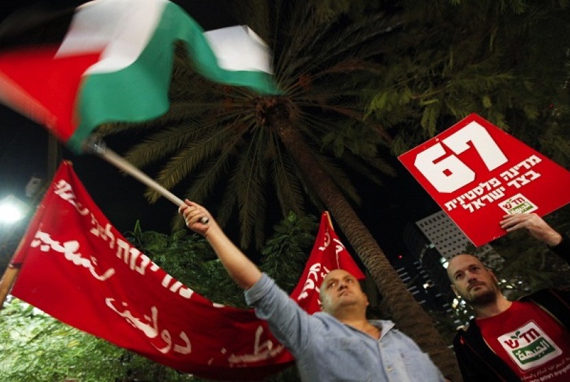 An Israeli man waves a Palestinian flag during a rally in Tel Aviv, supporting the Palestinian Authority's efforts to secure a diplomatic upgrade at the United Nations November 29, 2012. Some 300 Israelis took part in the rally on Thursday, several hours before the Palestinian Authority is expected to win an upgrade of its observer status at the United Nations from 
