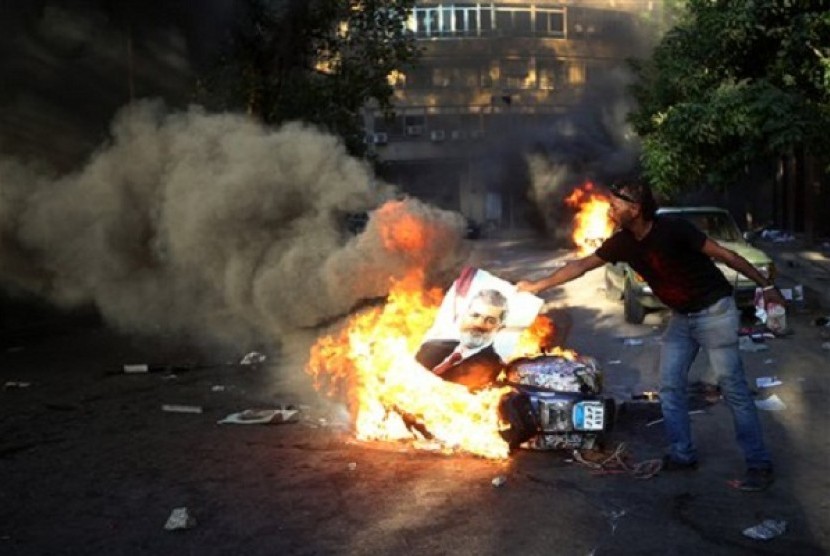 An opponent of ousted President Mohammed Morsi burns a poster of the former leader during clashes against Morsi supporters, in Cairo, Egypt, Monday, July 22, 2013. 