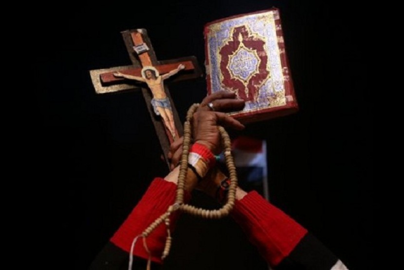 An opponent of ousted President Mohammed Morsi holds up Islam's holy book Quran (right) and Christian cross to show unity during a rally at Tahrir square, in Cairo, Egypt, late Friday, July 19, 2013. 