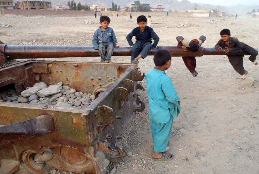 Anak-anak Afghanistan bermain di bangkai tank Soviet di distrik Behsood Jalalabad, Afghanistan, Senin (18/2). (AP/Rahmat Gul)