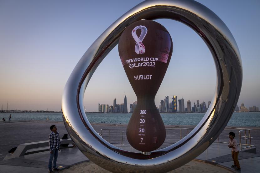  Anak-anak berdiri di sebelah jam hitung mundur resmi yang menunjukkan sisa waktu hingga kick-off Piala Dunia 2022, di Doha, Qatar, 25 November 2021. Turki Kirim 3.250 Personel Keamanan Jaga Piala Dunia Qatar 2022