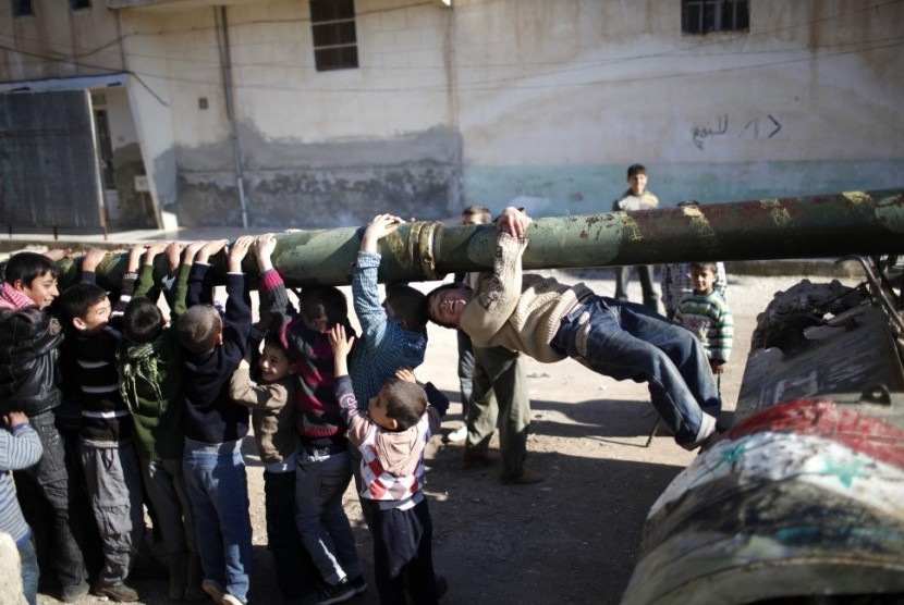 Anak-anak bergelantungan di sebuah tank di Kota Azaz, Suriah.