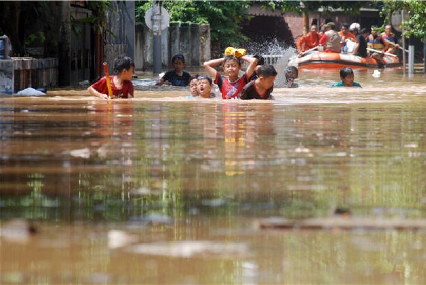 Anak-anak berjalan melawan genangan banjir yang melanda Jakarta. (ilustrasi) 
