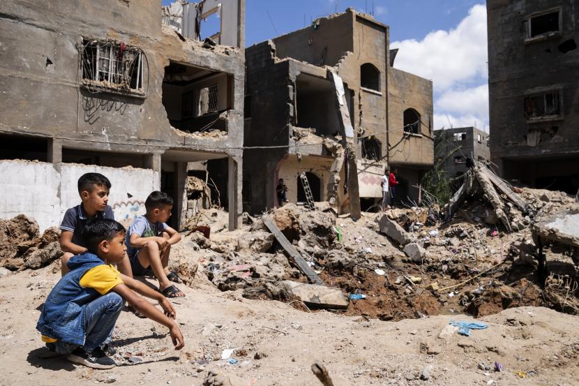 Anak-anak berkumpul di samping kawah tempat rumah Ramez al-Masri dihancurkan oleh serangan udara sebelum gencatan senjata tercapai setelah perang 11 hari antara penguasa Hamas Gaza dan Israel, Minggu, 23 Mei 2021, di Beit Hanoun. , Jalur Gaza utara.