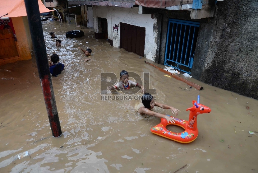 Anak-anak bermain air saat banjir menggenangi Kampung Pulo, Jakarta, Senin (16/11).  (Republika/Yasin Habibi)