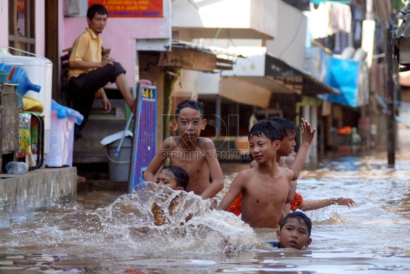  Anak-anak bermain dalam genangan air banjir di Kawasan Jatinegara,Jakarta Timur,Rabu (13/2). (Republika/Prayogi)