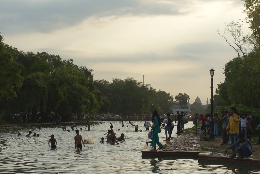 Anak-anak bermain dan berenang di kolam air mancur monumen India Gate, New Delhi, India, Senin (12/8). 