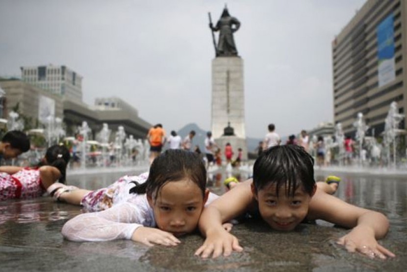 Anak-anak bermain di air terjun di tengah udara musim panas di Gwanghwamun, Seoul, Juli 2014. Total populasi Korea Selatan diperkirakan akan turun dari 51,75 juta pada 2024 