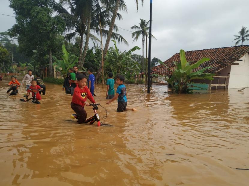  Anak-anak bermain di tengah banjir yang menggenang jalan di Desa Tanjungsari, Kecamatan Sukaresik, Kabupaten Tasikmalaya, Rabu (10/6).