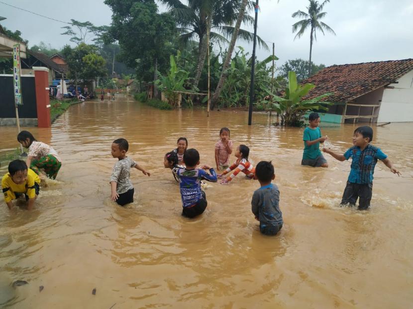  Anak-anak bermain di tengah banjir yang menggenang jalan di Desa Tanjungsari, Kecamatan Sukaresik, Kabupaten Tasikmalaya, Rabu (10/6).