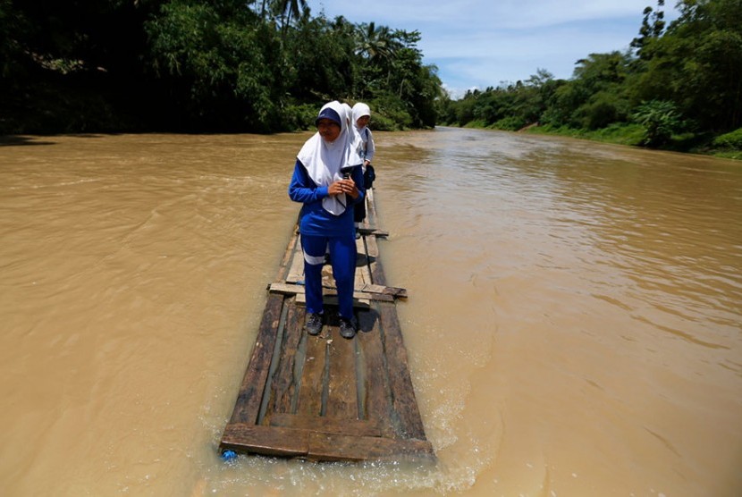 Anak-anak harus memakai perahu getek untuk menyeberang Sungai Ciherang.