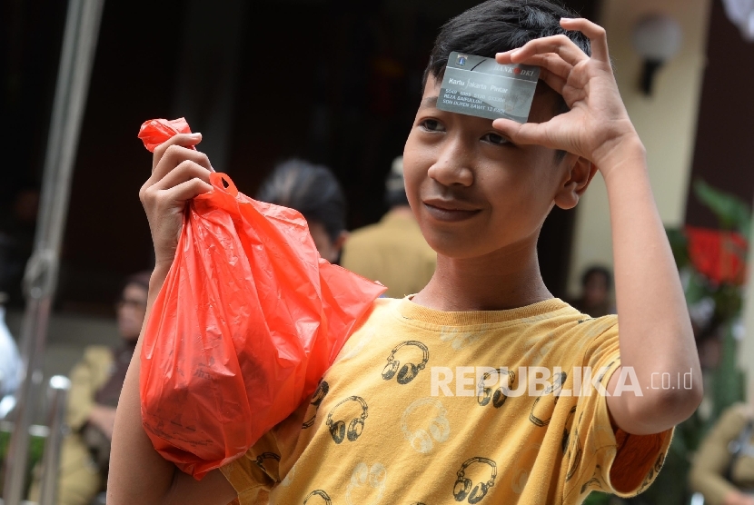 Anak-anak didampingi orang tua pemegang Kartu Jakarta Pintar (KJP) mengantre untuk membeli daging bersubsidi. Pemkot Jakarta Barat memastikan akan mencabut KJP siswa terbukti terlibat tawuran.