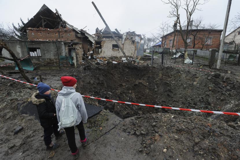Anak-anak melihat kawah yang tercipta akibat ledakan di daerah pemukiman setelah penembakan Rusia di Solonka, wilayah Lviv, Ukraina, Rabu, 16 November 2022.  Turki memastikan keamanan dari anak-anak yatim piatu dari Ukraina.