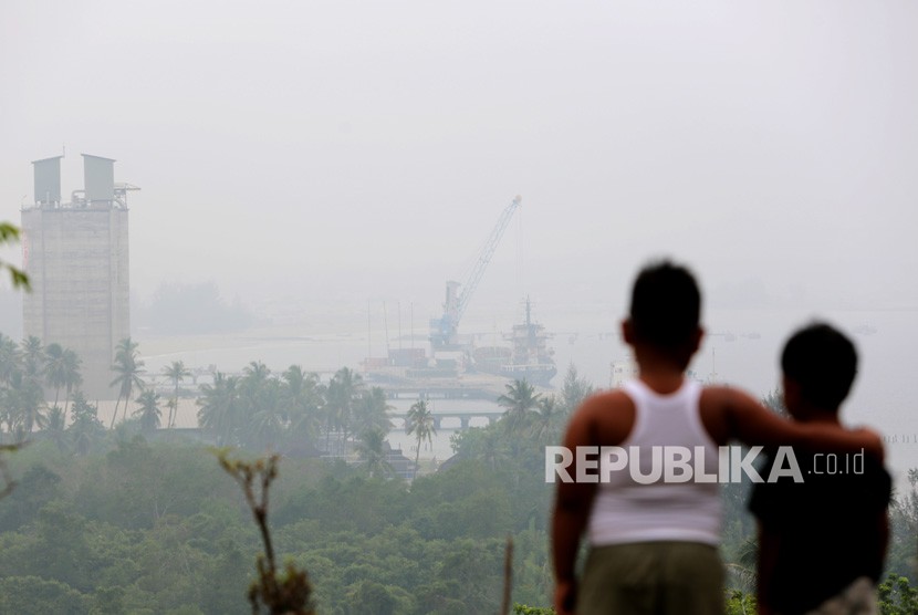Anak-anak melihat Pelabuhan Malahayati yang diselimuti kabut asap di Krueng Raya, Aceh Besar, Aceh, Senin (23/9/2019). Polusi udara berdampak buruk bagi kesehatan anak.