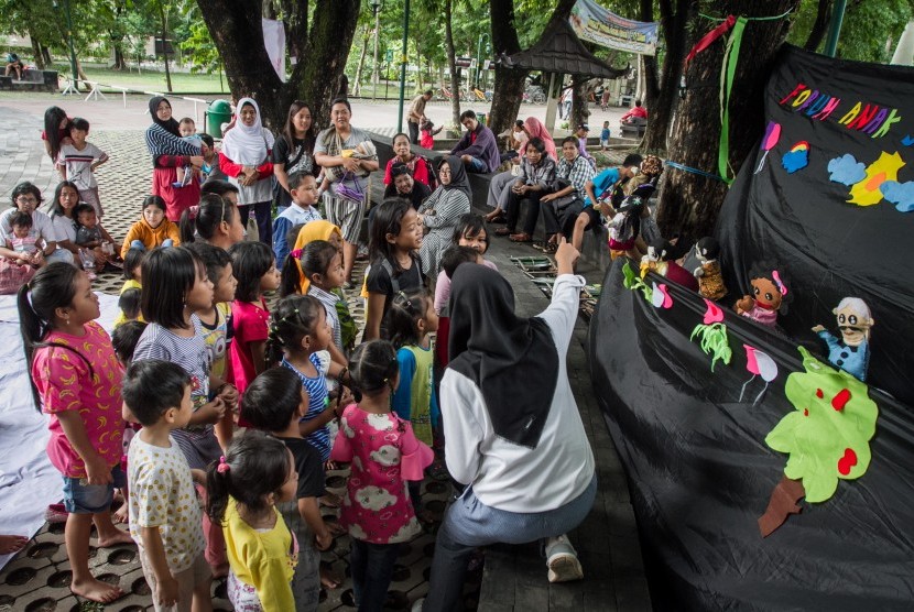 Anak-anak melihat penampilan pentas boneka tangan pada acara Hari Jadi Forum Anak Surakarta ke-12 di Monumen Banjarsari, Solo, Jawa Tengah, Minggu (16/12/2018).