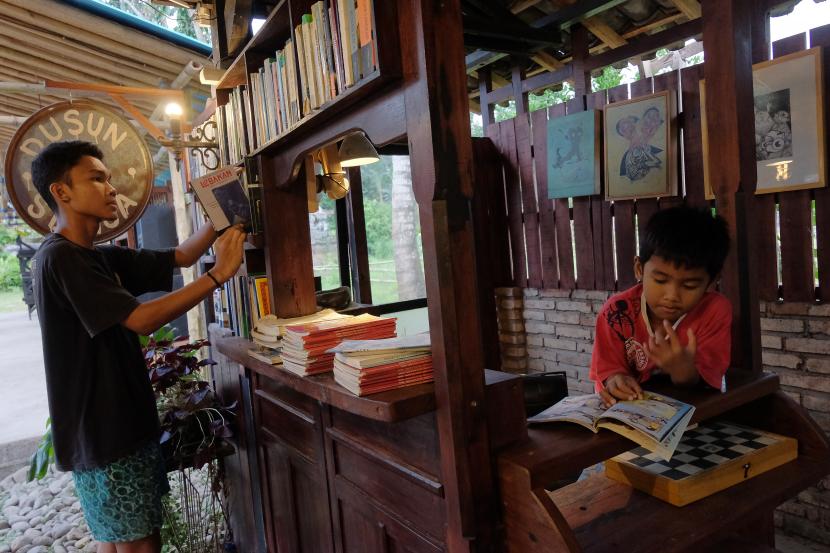 Anak-anak membaca buku di perpustakaan Dusun Senja, Desa Candikusuma, Jembrana, Bali. Perpustakaan di kawasan desa kreatif yang merupakan program dari Kementerian Pariwisata dan Ekonomi Kreatif (Kemenparekraf) tersebut dibuka untuk menarik minat baca anak-anak yang tinggal di pelosok desa itu. 