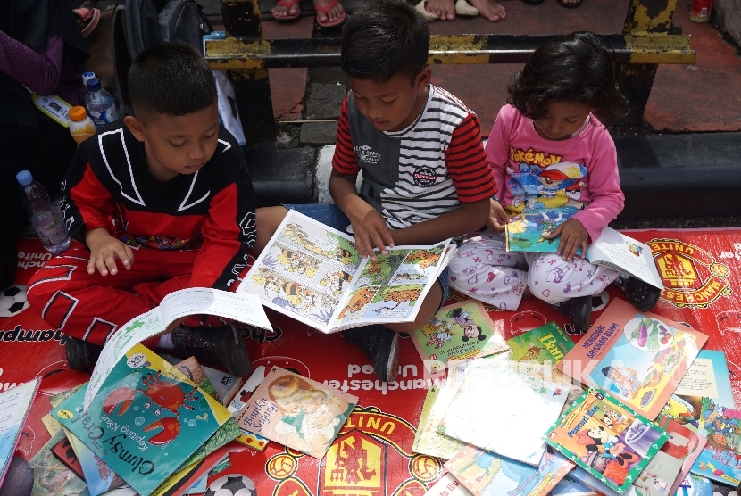  Anak-anak membaca buku di stand komunitas Buku 100 Desa saat berlansungya Car Free Day di Bundaran HI, Jakarta, Ahad (2/4). 