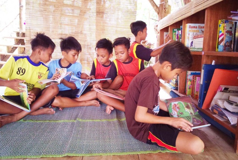 Anak-anak membaca di perpustakaan Bale Tau, Desa Batukaras, Kecamatan Cijulang, Kabupaten Pangandaran.