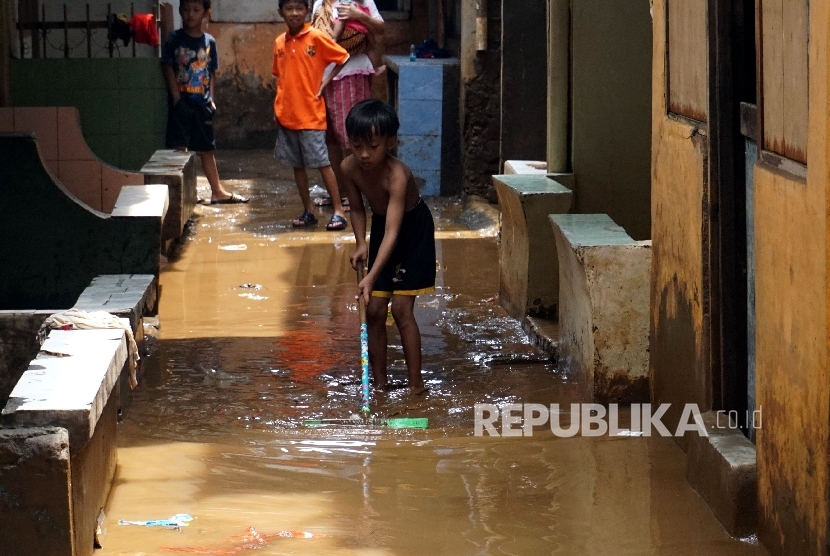 Anak-anak membersihkan lumpur ketika banjir menggenangi kawasan Kebon Pala, Jakarta Timur, Selasa (28/2).