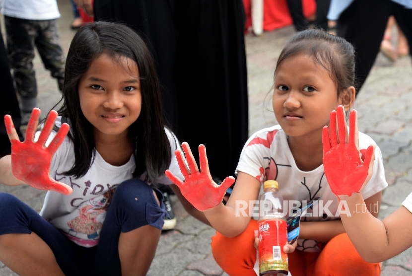 Anak-anak menunjukan tangannya seusai memberikan cap tangan dikain putih dalam kegiatan Cap Telapak Tangan Cinta untuk Rohingya di halaman parkir Sarinah, Jakarta, Ahad (10/9).