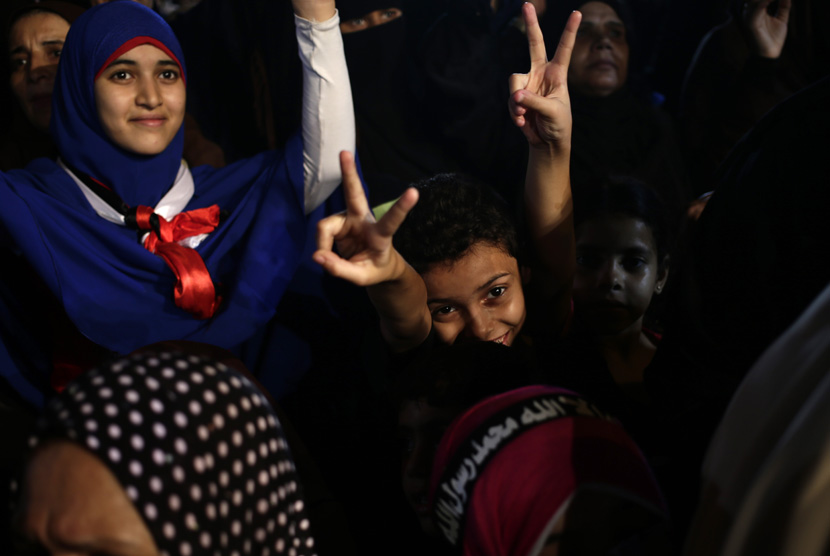  Anak-anak Mesir mengacungkan jari tanda kemenangan saat bergabung dengan aksi unjuk rasa menolak kudeta dan mendukung Presiden Mursi di luar Masjid Rabiah Al Adawiyah, Nasr City, Kairo, Rabu (31/7).   (AP / Khalil Hamra)