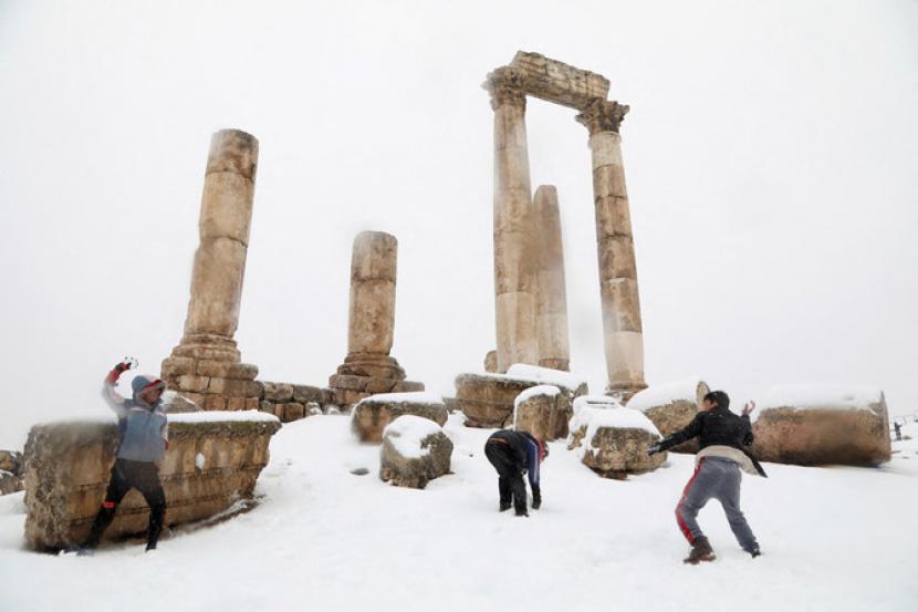 Anak-anak pengungsi bermain di Kuil Hercules Romawi di Amman Citadel yang tertutup salju di Amman, Yordania, 27 Januari 2022. Salju Selimuti Yordania, Menambah Derita  Pengungsi