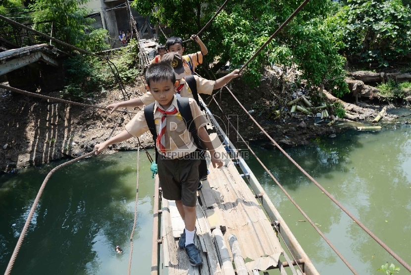 Anak-anak pulang sekolah menyeberangi Kali Angke melalui jembatan rapuh di Kampung Cantiga, Petir, Cipondoh, Tangerang (02/09).  (Republika/Yasin Habibi)