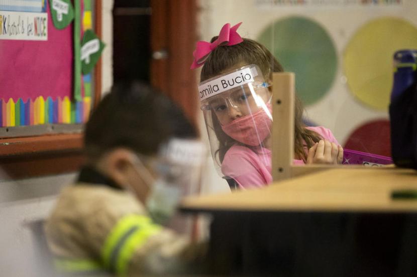 Anak-anak TK Resurrection Catholic School di Boyle Heights, East Los Angeles, California, AS mengenakan masker dan pelindung wajah saat sekolah di tengah pandemi Covid-19 pada 1 February 2021. Penting bagi orang tua untuk memilih masker yang nyaman bagi anak agar anak mau menggunakannya selagi di luar rumah.