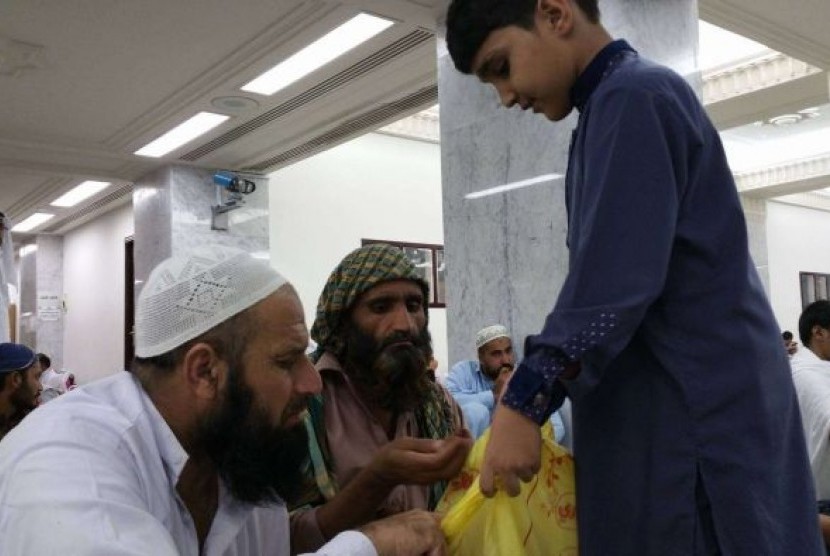 Anak-anak yang membagikan kurma, cokelat, permen kepada jamaah Masjidil Haram usai melaksanakan Shalat Idul Fitri, Rabu (6/7).