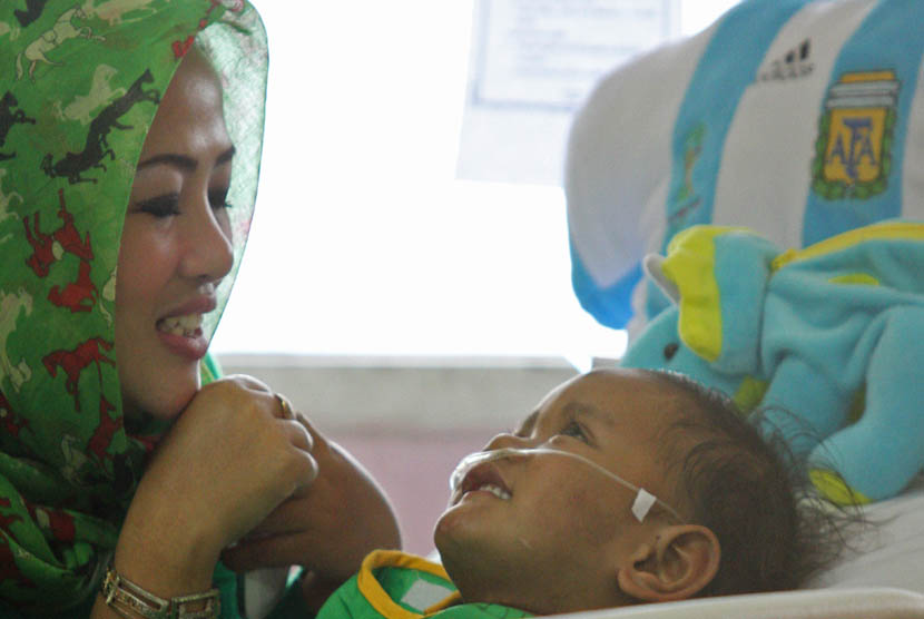 Anak balita korban penculikan dan penyiksaan, Iqbal Saputra 3,5 thn (kanan) didampingi pendamping dari Lembaga Perlindungan Anak Sudin Sosial Jakarta Utara Rika Sutio (kiri) di ruang Paediatrik Intensif Care Unit (PICU) RSUD Koja, Jakarta, Senin (24/3). 