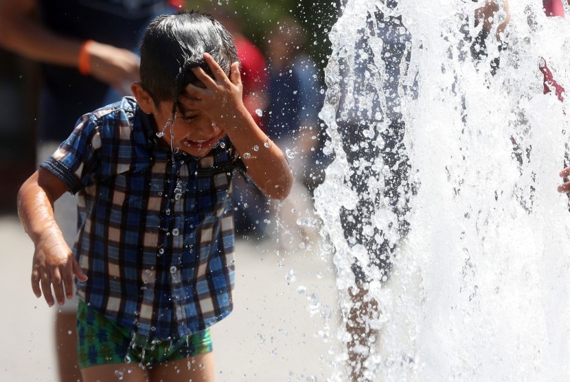 Anak bermain dengan air saat hawa sangat panas di Santiago, Cile.