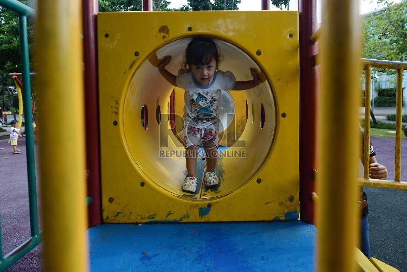 Anak didampingi orang tuanya bermain di area Taman Menteng, Jakarta Pusat, Selasa (17/2).  (Republika/Raisan Al Farisi)
