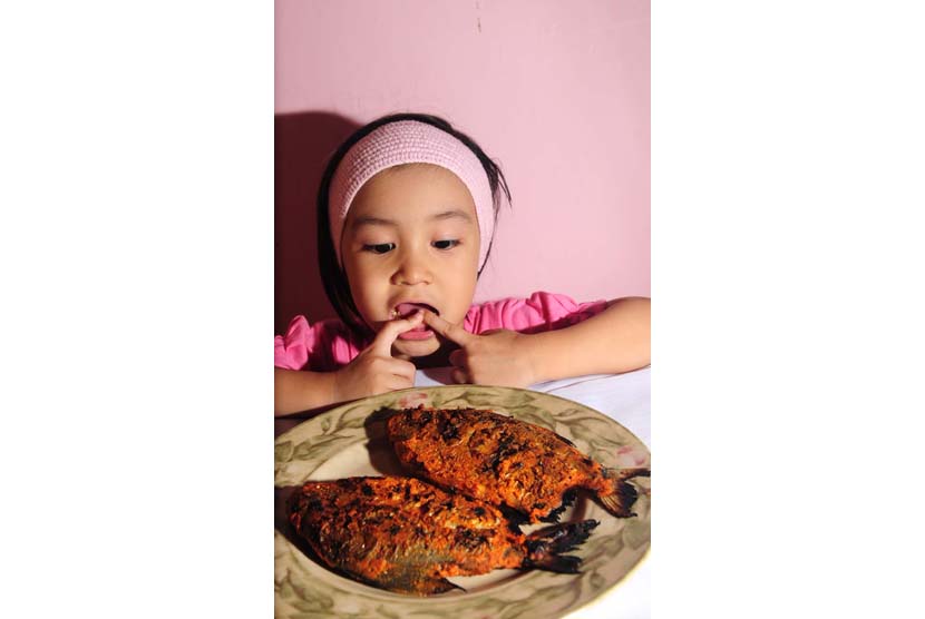 Anak makan ikan (ilustrasi).