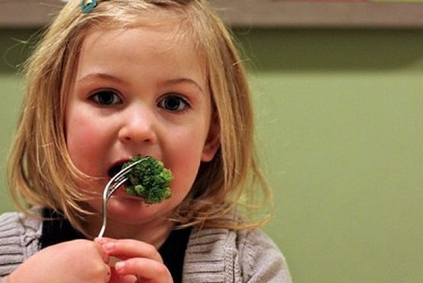Anak memakan sayuran. 
