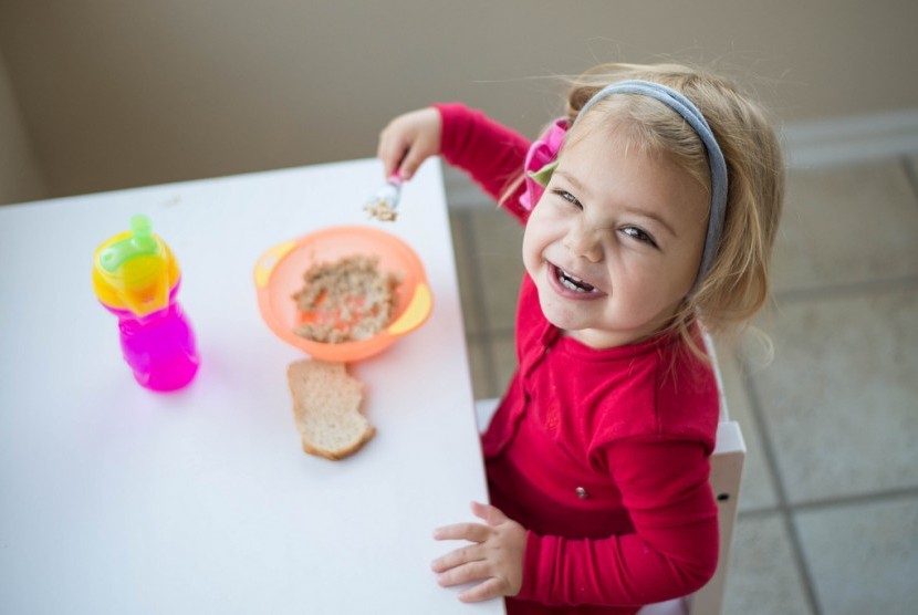 Anak sedang sarapan. Jika tak terbiasa sarapan, orang tua harus mengubah pola makan dan konsisten menjalaninya.