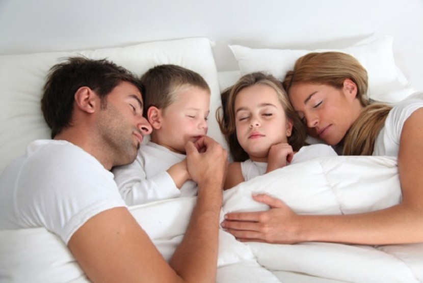 Anak tidur bersama orang tua. Ikut berbaring sampai anak tertidur merupakan bentuk attachment parenting.